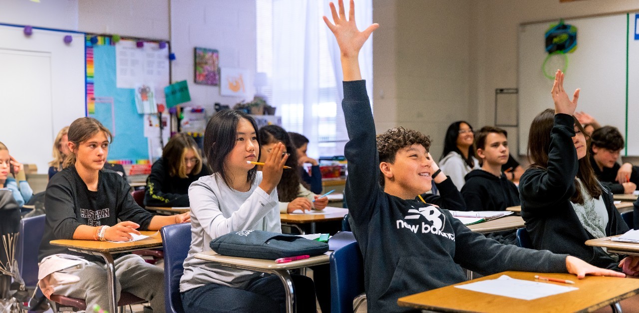 students in class raising their hands